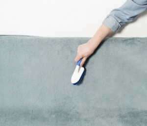 Front view of woman brushing textile upholstery during professional cleaning service by Alamo Steam Team in San Antonio, TX