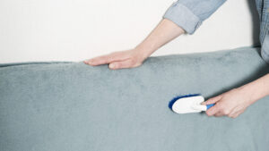 Woman brushing textile upholstery during professional cleaning service by Alamo Steam Team in San Antonio, TX